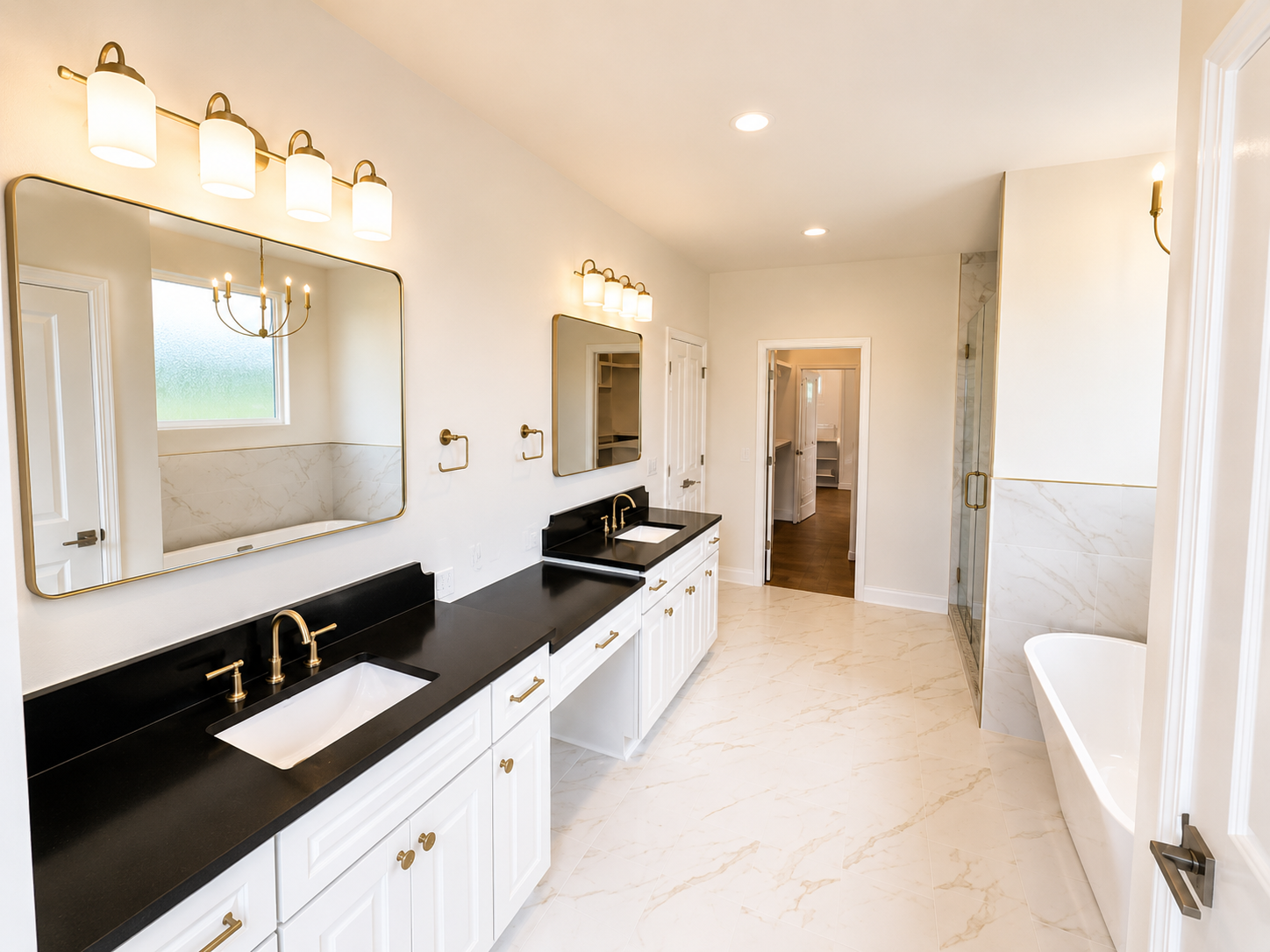Primary bath with dual black quartz vanities, brass mirrors, and freestanding tub