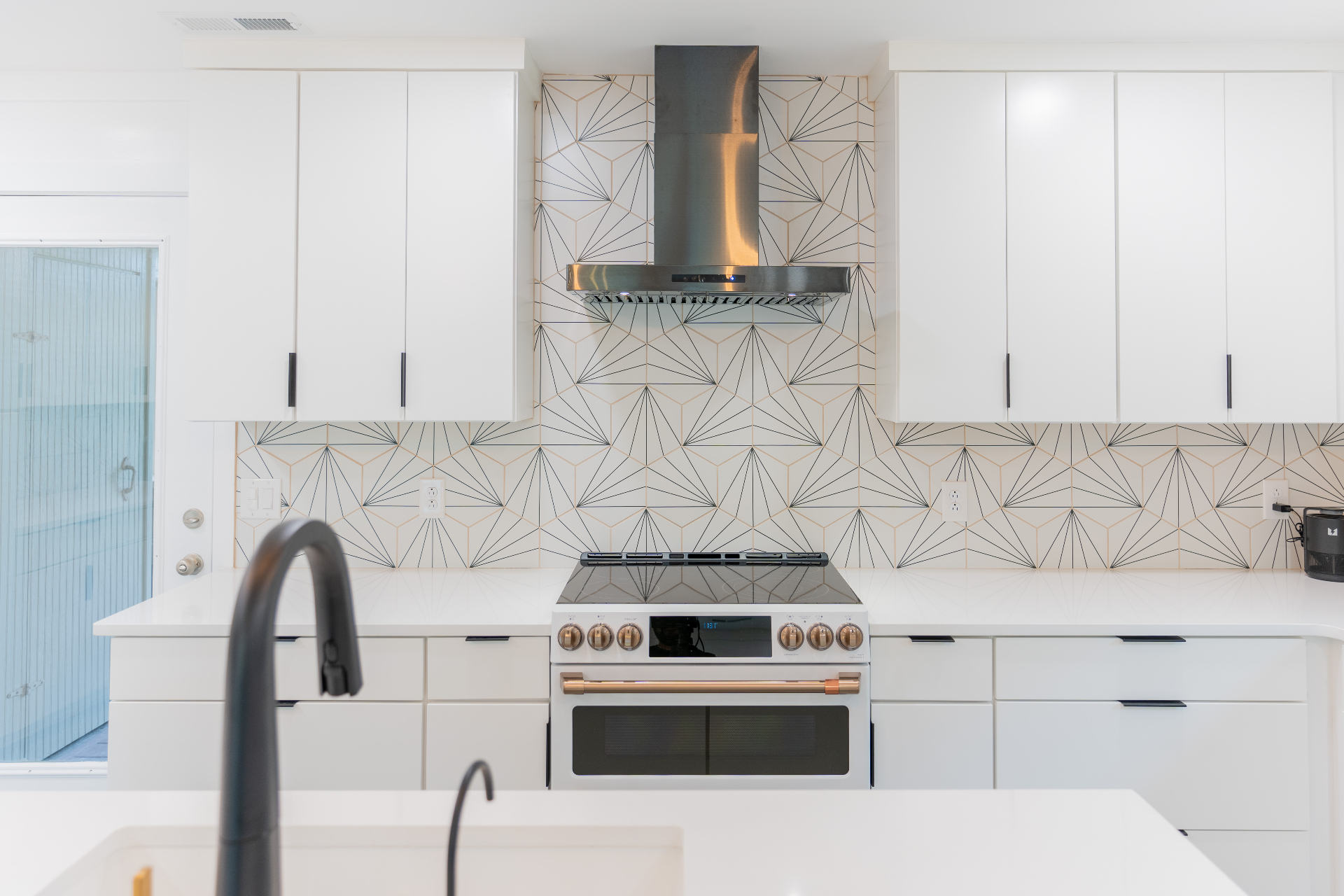 Geometric tile backsplash with stainless hood and gas range