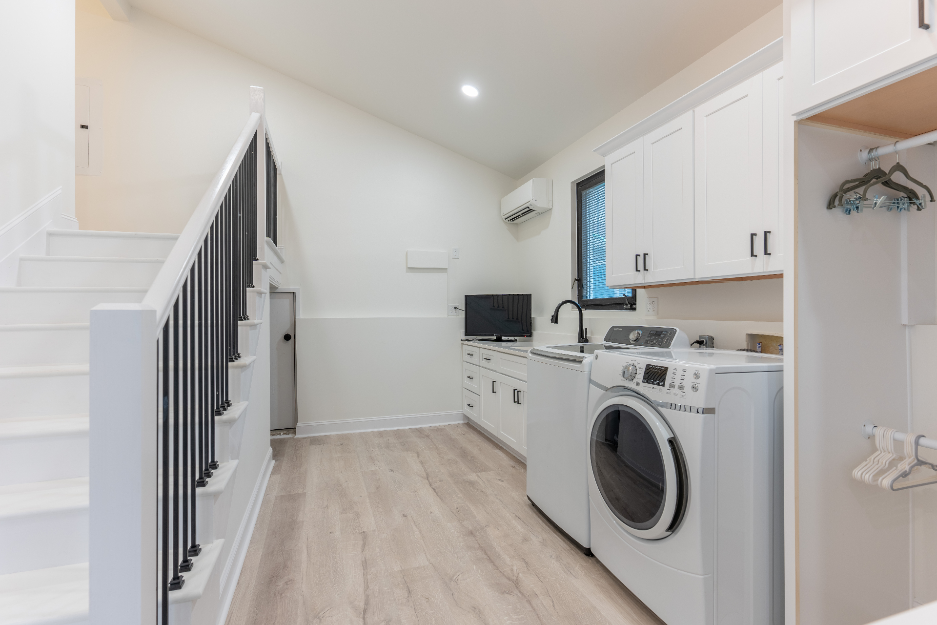 Laundry room with custom cabinetry, utility sink, and interior stair connection