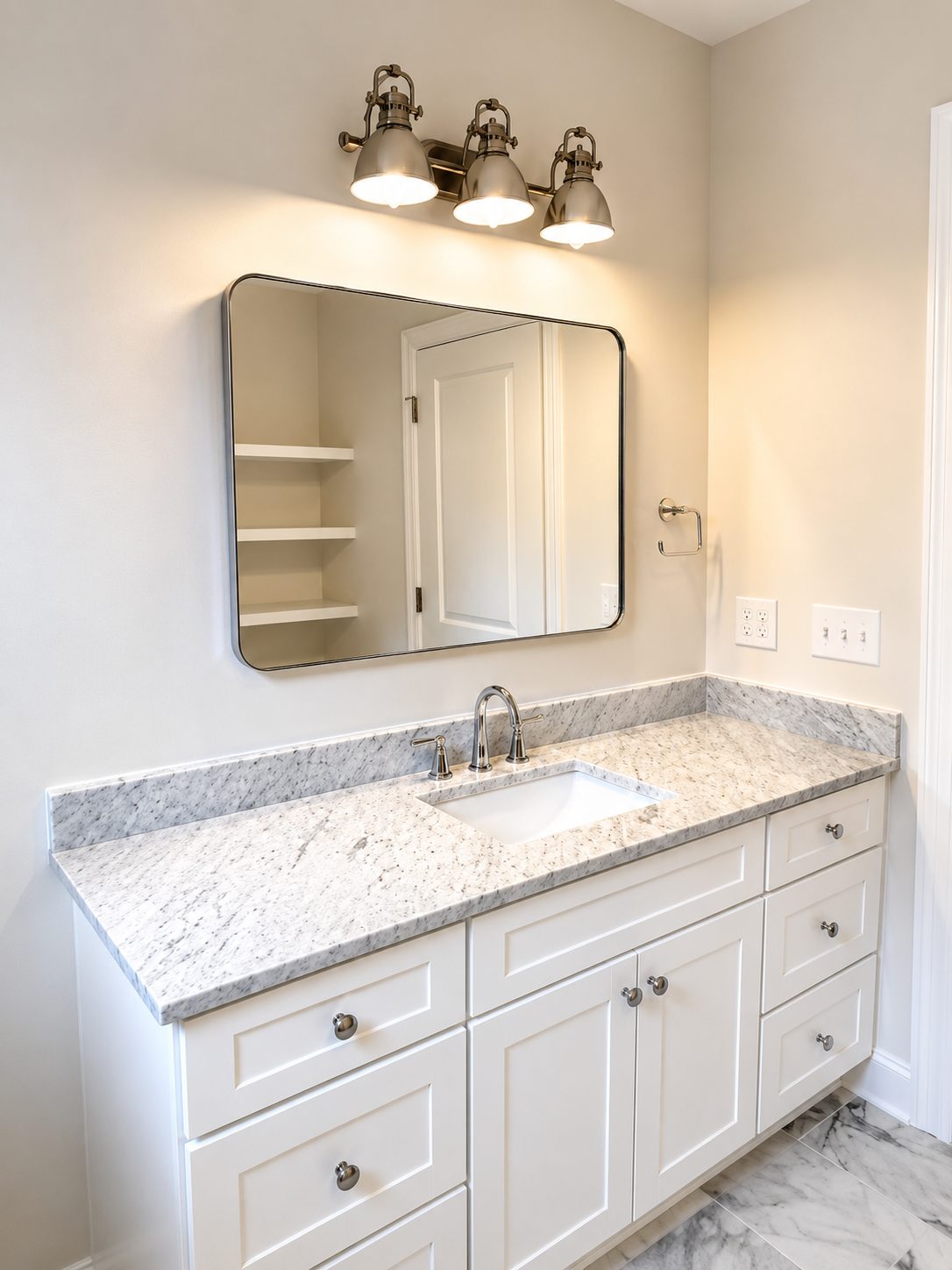 Vanity with granite countertop, framed mirror, and brushed nickel lighting