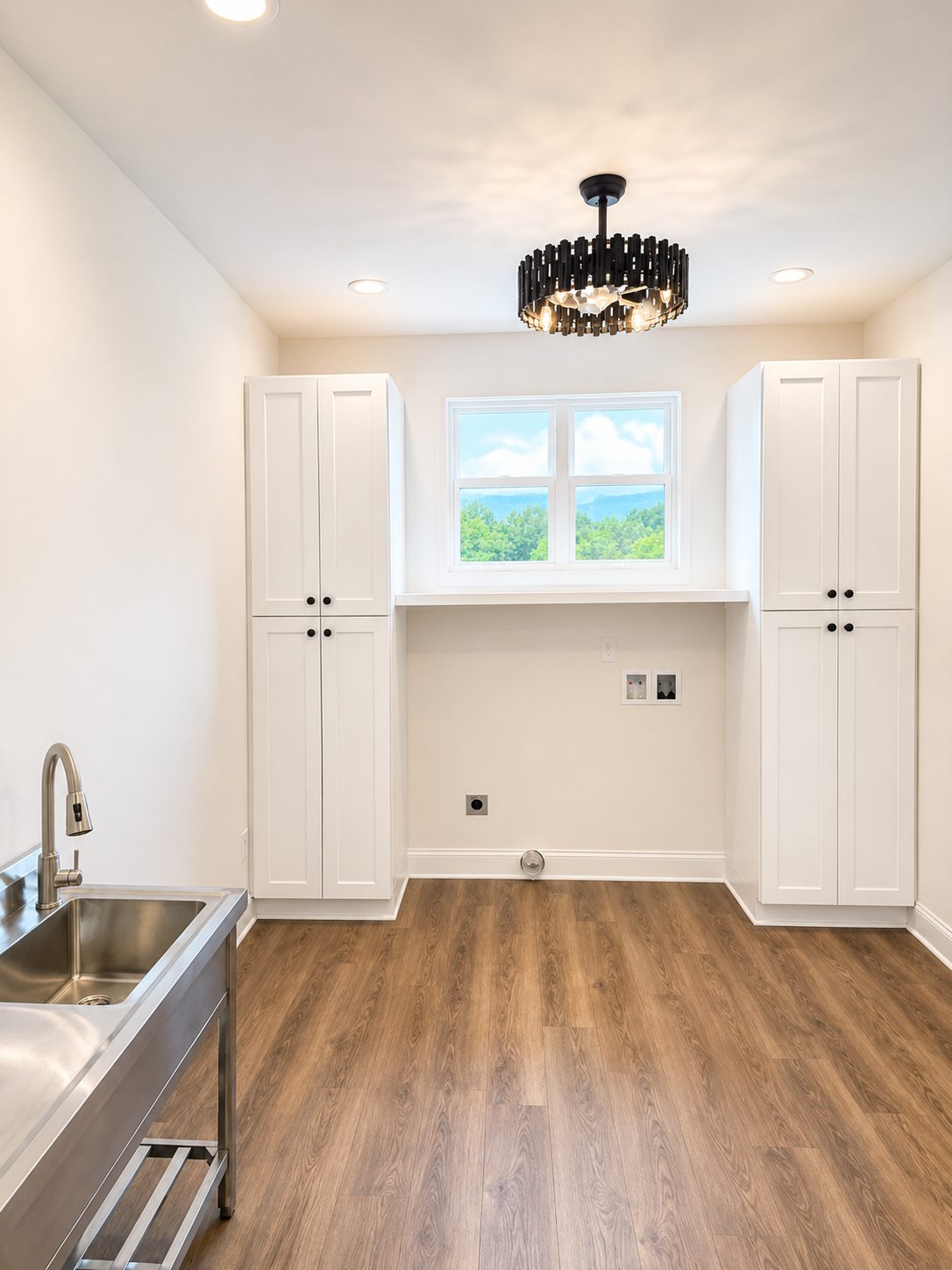 Laundry room with floor-to-ceiling cabinetry, utility sink, and window light