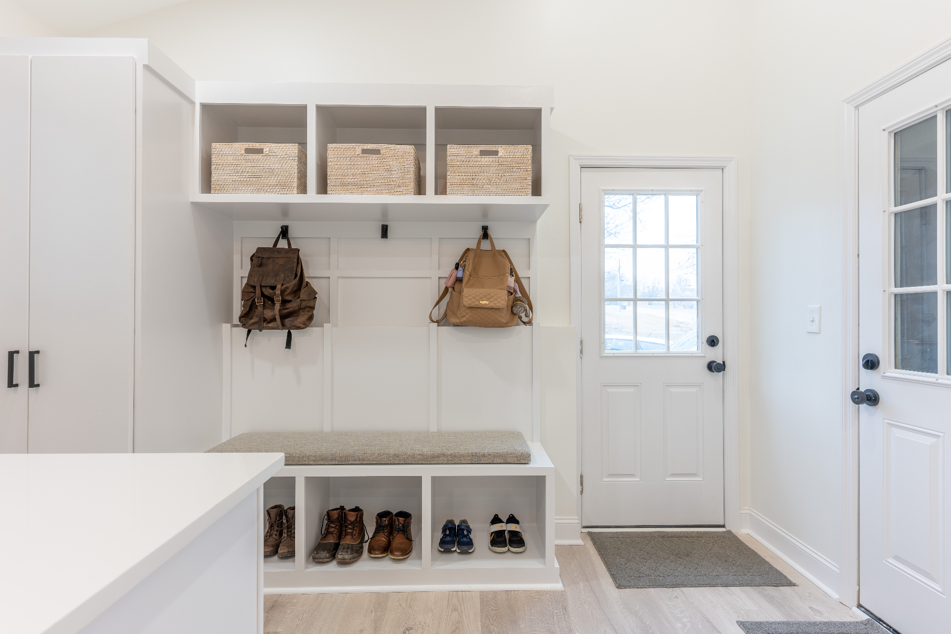Mudroom drop zone with bench seating, cubbies, and exterior access
